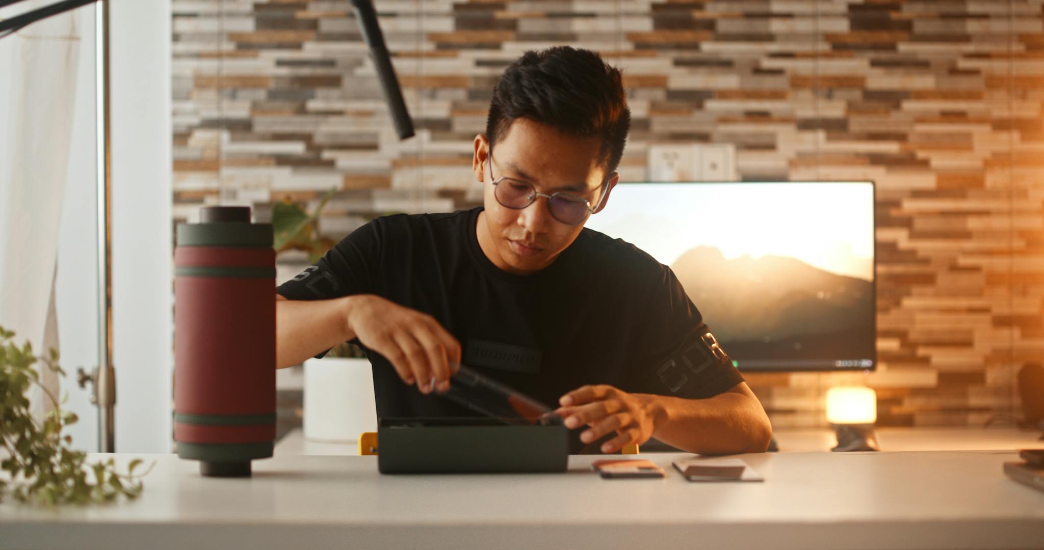 A young man unboxes a smartphone, showcasing modern technology in a cozy indoor setting.